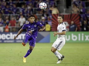 Orlando City 's Cristian Higuita, left, clears the ball past Vancouver Whitecaps's Nicolas Mezquida (11) during the first half of an MLS soccer match, Saturday, Aug. 26, 2017, in Orlando, Fla. (AP Photo/John Raoux)