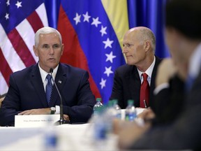 Florida Gov. Rick Scott listens at right as Vice President Mike Pence speaks during a meeting with members of the Venezuelan exile community, at Our Lady of Guadalupe Catholic Church, Wednesday, Aug. 23, 2017, in Doral, Fla. (AP Photo/Lynne Sladky)