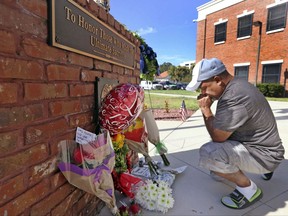 CORRECTS STATUS OF SECOND POLICE OFFICER - After placing flowers at a makeshift memorial, Miguel Velez, say's a prayer for the officer that was killed on Saturday, Aug. 19, 2017 in Kissimmee, Fla.   The Kissimmee Police Department says Sgt. Sam Howard died Saturday from his injuries. His colleague, Officer Matthew Baxter, died Friday night after the attack in a neighborhood of Kissimmee, located south of the theme park hub of Orlando.   (Red Huber/Orlando Sentinel via AP)