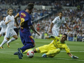 Barcelona's Lionel Messi, left, challenges Real Madrid's goalkeeper Keylor Navas during the Spanish Super Cup second leg soccer match between Real Madrid and Barcelona at the Santiago Bernabeu stadium in Madrid, Wednesday, Aug. 16, 2017. (AP Photo/Francisco Seco)