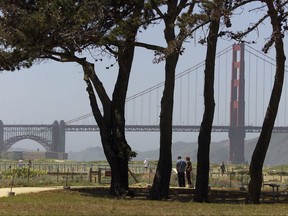 File - In this May 1, 2001 file photo, a couple looks at an educational marker beneath some trees at Crissy Field with the Golden Gate Bridge in the background in San Francisco. Crissy Field is the site of a rally Saturday, Aug. 26, 2017, by the conservative group Patriot Prayer. Northern California police and civic leaders are hoping for calm, but bracing for violence this weekend when hundreds, possibly thousands, of demonstrators of all stripes flock to the San Francisco Bay Area for dueling political rallies. (AP Photo/Eric Risberg, File)