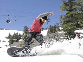 FILE - In this July 1, 2017 file photo, a snow boarder cuts throughout the snow at the Squaw Valley Ski Resort in Squaw Valley, Calif. A ski resort at Lake Tahoe has announced a new partnership with a leading outdoor retailer in China to try to help attract more Chinese skiers and snowboarders to the region. The agreement between Squaw Valley Alpine Meadows and Toread builds on the Sierra resort's existing alliance with China's Genting Resort Secret Garden. (AP Photo/Rich Pedroncelli, File)