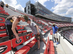 Jake Flyn, from left, and Allyn Hickey join dozens of workers preparing the home of the Georgia Bulldogs, Sanford Stadium, for eclipse viewing and the beginning of NCAA college football season, Sunday, Aug. 20, 2017, in Athens, Ga.