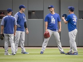 Los Angeles Dodgers' Yu Darvish, second from right, Austin Barnes, left, Alex Wood, and Joc Pederson, right, talk in the outfield as the Dodgers warm up before a baseball game against the Atlanta Braves, Wednesday, Aug. 2, 2017, in Atlanta. Darvish was recently acquired from the Texas Rangers. (AP Photo/John Amis)