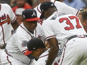 Atlanta Braves shortstop Johan Camargo is helped up by third base coach Ron Washington (37) and bench coach Terry Pendleton, left, after collapsing as he took the field before a baseball game against the Philadelphia Phillies, Tuesday, Aug. 8, 2017, in Atlanta. Jace Peterson took his place to start the game at shortstop. (AP Photo/John Amis)