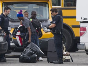 Asylum seekers remove their belongings from a truck at a processing centre at the Canada-United States border in Lacolle, Que. Thursday, August 10, 2017. THE CANADIAN PRESS/Graham Hughes