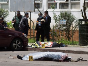 Two bodies, one identified as a prison guard, lie covered outside the Roosevelt Hospital in Guatemala City after an assault by gunmen on Aug. 16, 2017.