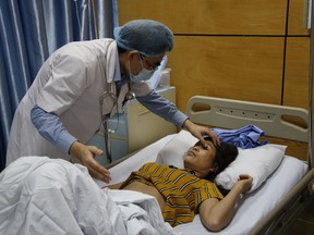 Doctor Vu Minh Dien, left, examines dengue patient Tran Thi Xuyen at the National Hospital of Tropical Diseases in Hanoi, Vietnam, Friday, Aug. 18, 2017. Vietnam has been battling raging dengue fever outbreaks with more than 10,000 new infections reported over the past week stretching its medical system. (AP Photo/Tran Van Minh)