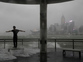 A man plays with strong wind caused by typhoon Hato on the waterfront of Victoria Habour in Hong Kong, Wednesday, Aug. 23, 2017.