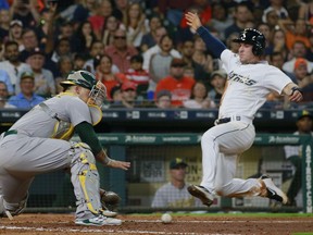 Oakland Athletics catcher Bruce Maxwell, left, reaches for the ball before tagging out Houston Astros' Alex Bregman at home on a throw from center fielder Boog Powell in the fifth inning of a baseball game Saturday, Aug. 29, 2017, in Houston. (AP Photo/Richard Carson)
