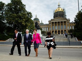 Apple CEO Tim Cook, second from left, and Iowa Gov. Kim Reynolds, third from left, walk to a podium in front of the Capitol building, background, in Des Moines, Iowa, Thursday, Aug. 24, 2017, to announce Apple's plans for two new data storage centers and to create at least 50 jobs near Des Moines. (Brian Powers/The Des Moines Register via AP)