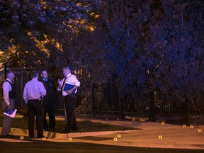 In this Aug. 8, 2017 photo, Chicago Police investigate a shooting near East 37th Street and  South Michigan Avenue, about two blocks from the Chicago Police Department headquarters. Police say several gunmen opened fire on a group of people standing on a Chicago sidewalk, killing one and wounding six others. (Ashlee Rezin/Sun Times via AP)