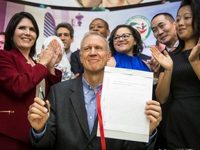 Illinois Gov. Bruce Rauner smiles while surrounded by law enforcement officials and immigrant rights activists in Chicago's Pilsen neighborhood Monday, Aug. 28, 2017, after signing legislation that will limit how local and state police can cooperate with federal immigration authorities. The narrow measure prohibits police from searching, arresting or detaining someone solely because of immigration status, or because of so-called federal immigration detainers. (Ashlee Rezin/Chicago Sun-Times via AP)