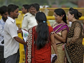 A roadside photographer shows a photo album to women at India Gate monument in New Delhi, India, Friday, Aug. 4, 2017. Police are investigating a mysterious raft of attacks in which Indian women say they're waking up to find someone has chopped off their hair.