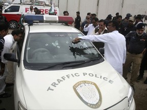 Pakistani officials look at a police vehicle ambushed by unknown gunmen in Karachi, Pakistan, Friday, Aug. 11, 2017. Police say gunmen riding a motorcycle have opened fire on a vehicle carrying a senior police officer in southern Pakistan, killing him and his guard before fleeing. (AP Photo/Fareed Khan)