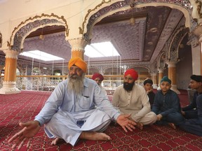 In this Tuesday, Aug. 8, 2017 photo, Pakistani Sikh Radesh Singh, left, talks at a temple in Peshawar, Pakistan. Singh's said that his grandfather was just 11 years old when he left his "simple village" in India's Punjab province to move to Peshawar, in the far northwest of the country on the border with Afghanistan. Seventy years after Partition of the Indian subcontinent, Pakistan's Sikhs say neither India nor Pakistan feels like home for a young generation searching for peace and security elsewhere. (AP Photo/Muhammad Sajjad)