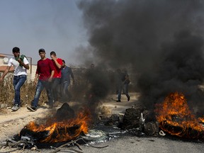 Palestinian protesters burn tires and clash with Israeli army soldiers after troops searched and measured the family house of Omar al-Abed, 20, identified by the Israeli army as the assailant of yesterday's attack at the Israeli settlement of Halamish, in preparation for demolition, in the West Bank village of Kobar, near Ramallah, Saturday, July 22, 2017.