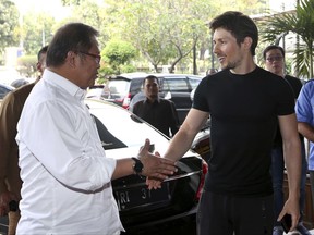 Indonesian Communication and Information Minister Rudiantara, left, shakes hands with Telegram co-founder Pavel Durov during their meeting in Jakarta, Indonesia, Tuesday, Aug. 1, 2017. The Indonesian government has lifted its threat to ban the encrypted messaging app Telegram because it's taking steps to address "negative" content that includes forums for Islamic State group supporters, Rudiantara said Tuesday. (AP Photo/Tatan Syuflana)