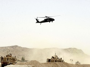 A US military helicopter flies over the site of a suicide bomb that struck a NATO convoy in Kandahar south of Kabul, Afghanistan, Wednesday, Aug. 2, 2017.