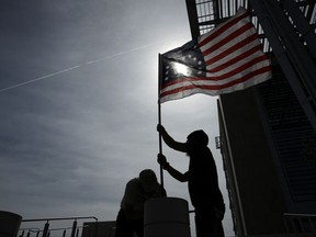 FILE - In this April 24, 2017, file photo, supporters raise a flag outside of the federal courthouse in Las Vegas. A retrial is nearing an end in Nevada for four men facing decades in prison for bringing assault-style weapons to a confrontation that stopped government agents from rounding up cattle near anti-government figure Cliven Bundy's ranch in April 2014. (AP Photo/John Locher, File)