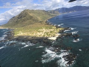 In this Friday, Aug. 18, 2017, photo taken through a helicopter glass window, provided by the U.S. Coast Guard, an MH-65 helicopter crew from Coast Guard Air Station Barbers Point passes Ka'ena Point in Hawaii. Officials have suspended the search for five Army soldiers in a helicopter crash during offshore training in Hawaii on Monday, Aug. 21, 2017. (U.S. Coast Guard via AP, File)