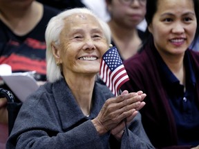 Hong Inh waves an American flag and smiles after taking the oath to become a United States citizen at the Los Angeles Convention Center, Tuesday, Aug. 22, 2017. At 103, the Cambodian woman was the oldest of more than 10,000 people who took the oath of allegiance. Three generations of her family were with her, including her 80-year-old daughter and teenage great-granddaughters. (AP Photo/Richard Vogel)