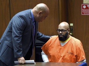 FILE - In this March 9, 2015, file photo, defense attorney Mathew Fletcher, left, talks with his client, Marion "Suge" Knight upon his arrival in court for a hearing about evidence in his murder case in Los Angeles. The former rap mogul and his lawyer discussed paying witnesses thousands of dollars to lie in his upcoming murder case, prosecutors said, Thursday, Aug. 10, 2017. Knight, whose Death Row Records made household names of Dr. Dre, Snoop Dogg and Tupac Shakur, is charged with running his truck into two men in 2015 outside a Compton burger stand after an argument on the set of the movie "Straight Outta Compton."   (AP Photo/Kevork Djansezian, Pool, File)