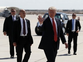 FILE - In this Tuesday, Aug. 22, 2017, file photo, President Donald Trump walks with his U.S. Secret Service protective detail as he waves before he departs on Air Force One in Yuma, Ariz. Some local officials in the border city of Yuma have expressed disappointment in the brevity of President Trump's visit, which they were hoping would give the community a higher profile on the national stage. The Yuma Sun reports that the initial plans for Trump's visit included a visit to the border and possible meetings with farmers and local politicians, but that didn't happen. (AP Photo/Alex Brandon, File)