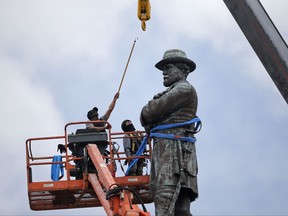 FILE- In this Friday, May 19, 2017, file photo, workers prepare to take down the statue of former Confederate Gen. Robert E. Lee, which stands over 100 feet tall, in Lee Circle in New Orleans. Lee monuments, memorials and schools in his name erected at the turn of the 20th Century are now facing scrutiny amid a demographically changing nation. Their removals are sparking heated clashes around the country just as the United States is celebrating the 150th anniversary of Reconstruction, the era when the United States tried to rebuild itself after the bloody Civil War. (AP Photo/Gerald Herbert, File)