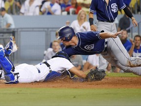 San Diego Padres' Hunter Renfroe, right, reaches for the base after being tagged out by Los Angeles Dodgers catcher Austin Barnes while trying to score on a single by Cory Spangenberg during the third inning of a baseball game, Friday, Aug. 11, 2017, in Los Angeles. (AP Photo/Mark J. Terrill)