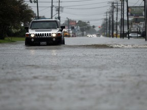 Cars drive through flooded streets in Lake Charles, La., as the city is receiving heavy rains from Tropical Storm Harvey, Sunday, Aug. 27, 2017. The storm came ashore on the Texas Gulf Coast as a category four hurricane. (AP Photo/Gerald Herbert)