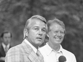 FILE - In this Aug. 20, 1976 file photo, Louisiana Gov. Edwin Edwards answers a reporter's question as Democratic nominee Jimmy Carter grins on in front of the Carter home, in Plains, Ga. Louisiana's four-term former governor Edwards is having an ostentatious 90th birthday bash, with a $250-per-person price tag to attend. The powerful and charismatic Edwards was the dominant figure in Louisiana politics for decades before he went to federal prison for a corruption conviction. Out of prison for six years, he's got a wife five decades his junior, a 4-year-old son and continued popularity in his home state. (AP Photo/Peter Bregg, File)