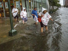 Philana Crite of Cleveland  in town for a family reunion, steps of the curb into flood waters at O'Keefe Avenue at Poydras Street Saturday, Aug. 5, 2017, after a deluge in the New Orleans area caused widespread flash flooding. (Scott Threlkeld/NOLA.com The Times-Picayune via AP)
