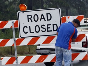 A resident replaces the closed road barrier along North Perkins Ferry Road in Moss Bluff, La., near Lake Charles, while rain from Tropical Storm Harvey continues to fall, Monday, Aug. 28, 2017. Authorities cautioned people from removing the barriers because accumulated high waters along those streets could swamp the vehicles and the wave action of passing vehicles might flood homes. (AP Photo/Rogelio V. Solis)