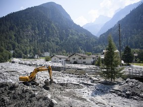 An excavator works on the landslide in Bondo, Graubuenden in southern Switzerland, Friday, August 25, 2017. Police in eastern Switzerland says some residents of a village pummeled by a rocky mudslide have been authorized to return home, as searchers resumed the hunt for eight missing people. (Gian Ehrenzeller/Keystone via AP)