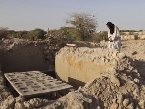 FILE - In this Friday, April 4, 2014 file photo, Mohamed Maouloud Ould Mohamed, a mausoleum caretaker, prays at a damaged tomb in Timbuktu, Mali. In the West African nation of Mali, Islamic radicals in 2012 overran Timbuktu, the historic city of Islamic culture. The International Criminal court ruled Thursday, Aug. 17, 2017, that a Muslim radical, Ahmad Al Faqi Al Mahdi, found guilty of destroying World Heritage cultural sites in the Malian city of Timbuktu must pay 2.7 million euros ($3.2 million) in reparations.  (AP Photo/Baba Ahmed, File)