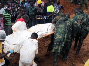 In this photo taken on Monday, Aug. 14, 2017 and provided by IFRC, Red Cross volunteers remove bodies from the scene of heavy flooding and mudslides in Regent, just outside of Sierra Leone's capital Freetown. The Red Cross estimates that 600 people are still missing as the death toll from massive mudslides in Sierra Leone's capital is certain to rise. Authorities say more than 300 were killed in and around Freetown following heavy rains. Many victims were trapped under tons of mud as they slept. An official says the local mortuary is "overwhelmed with corpses." (IFRC via AP)