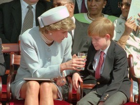 FILE - In this file photo dated Sunday May 7 1995,  Princess Diana offers her son Prince Harry a drink of water during a open air ceremony to mark the 50th anniversary of VE Day, the end of World War II in Europe, in Hyde Park, London.  Diana channeled Jackie Kennedy Onassis's style for an appearance on VE Day in 1995, appearing in a pale blue pillbox hat and matching suit. (AP Photo/Jacqueline Arzt, FILE)