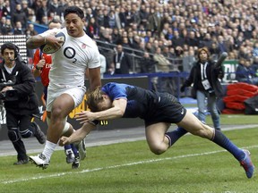 FILE - This is a Sunday, March 11, 2012  file photo of England's Manu Tuilagi, left, as he runs to score a try despite the tackle of France's Aurelien Rougerie during their six nations rugby union match at the Stade de France stadium, in Saint Denis, outside Paris, Sunday. England's Rugby Football Union said Monday Aug. 7, 2017 that  Manu Tuilagi and Denny Solomona  have been sent home from a national team training camp. An RFU statement says the disciplinary action is a result of "culture issues" with no further explanation provided. (AP Photo/Christophe Ena/File)