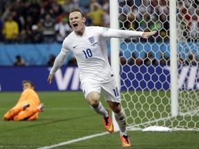 FILE - This is a Thursday, June 19, 2014 file photo of Uruguay's goalkeeper Fernando Muslera looks back as England's Wayne Rooney celebrates after scoring his side's first goal during the group D World Cup soccer match between Uruguay and England at the Itaquerao Stadium in Sao Paulo, Brazil.  England striker Wayne Rooney announced his immediate retirement from international football on Wednesday Aug. 23, 2017. (AP Photo/Kirsty Wigglesworth, File)