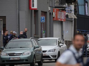 Police officers await developments in the Molenbeek suburb of Brussels, Tuesday, Aug. 8, 2017. Brussels police say that they opened fire on a vehicle after a high-speed chase in the suburb of Molenbeek and the driver told officers there are explosives inside. (AP Photo/Olivier Matthys)