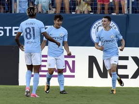 FILE - In this Saturday, July 29, 2017 file photo, Manchester City's Brahim Diaz, center, celebrates with teammates Demean Duhaney, left, and Phil Foden after scoring a goal against Tottenham Hotspur during an International Champions Cup match in Nashville, Tenn. The leap from City's academy to the star-filled first team has proved to be too big for most, but Foden appears good enough to make the transition. The diminutive 17-year-old midfielder impressed coach Pep Guardiola with his passing and technical qualities during City's tour to the United States in July and is set to be part of the senior squad for the coming season (AP Photo/Mark Zaleski, file)
