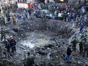 FILE- In this Monday, Feb. 14, 2005 file photo, rescue workers and soldiers stand around a massive crater after a bomb attack that tore through the motorcade of former Prime Minister Rafik Hariri in Beirut, Lebanon. The daughter of a victim of a 2005 bombing that killed Lebanon's former Prime Minister Rafik Hariri and 21 others has told an international court Monday, Aug. 28, 2017, about the frantic days of hunting for traces of father. (AP Photo, File)