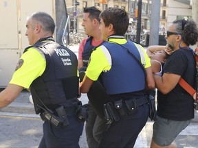 A woman is carried in Barcelona, Spain, Thursday, Aug. 17, 2017 after a white van jumped the sidewalk in the historic Las Ramblas district, crashing into a summer crowd of residents and tourists and injuring several people, police said. (AP Photo/Oriol Duran)