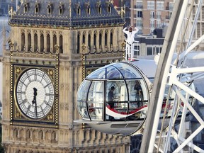 British athlete Mo Farah stands atop of a pod on the London Eye, with Big Ben's clock tower in background, as he bids a final farewell to British track competitive athletics after winning gold in the 10,000m and silver in the 5,000m at the IAAF World Championships in London, Sunday Aug. 13, 2017.  Farah is due to retire from the track at the end of the month, after the Diamond League in Zurich, and hopes to focus on the marathon distance. (Jonathan Brady/PA via AP)