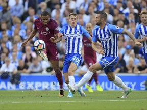 Manchester City's Danilo, left, and Brighton & Hove Albion's Solly March, centre, challenge for the ball during the Premier League soccer match Brighton and Hove Albion's versus Manchester City at the AMEX Stadium, Brighton, England, Saturday Aug. 12, 2017. (Gareth Fuller/PA via AP)