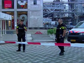 In this image taken from video officers stand behind a cordoned-off area in Rotterdam, Wednesday Aug. 23, 2017, after a concert by an American rock band was cancelled Wednesday night following a threat, the city's mayor said. Police detained the driver of a van with Spanish license plates carrying a number of gas tanks inside. (RTL via AP)