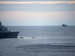 In this Saturday, Aug. 5, 2017, sailors man small boats as an MH-60S Sea Hawk helicopter, assigned to Helicopter Sea Combat Squadron (HSC) 25 flies overhead to recover personnel near the amphibious transport dock USS Green Bay (LPD 20) following an aviation mishap of an MV-22 Osprey, which caused the aircraft to enter the water off the coast of Australia.