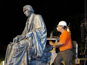 Workers positions the monument dedicated to U.S. Supreme Court Chief Justice Roger Brooke Taney on a flatbed truck after it was removed from outside Maryland State House, in Annapolis, Md., early Friday, Aug. 18, 2017. Maryland workers hauled several monuments away, days after a white nationalist rally in Charlottesville, Virginia, turned deadly. ( AP Photo/Jose Luis Magana)