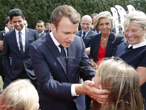 French President Emmanuel Macron greets while PSG President Nasser Al-Khelaifi, left, stands behind him as he attends at a charity holiday program event in Moisson, east of Paris, France, Thursday, Aug. 3, 2017. French President Emmanuel Macron is welcoming the likely arrival of Brazilian soccer star Neymar at Paris-Saint Germain in a record $262 million deal. (Philippe Wojazer/Pool Photo via AP)